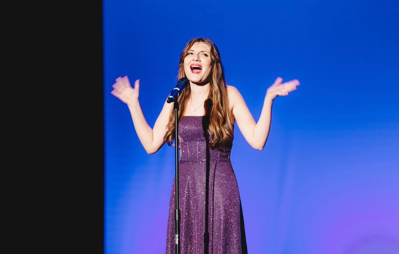 Savannah Lynn performing with arms raised at a microphone