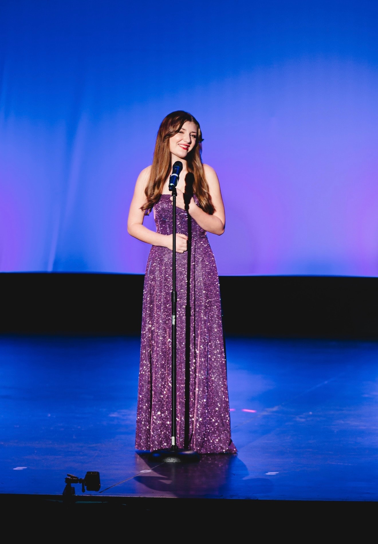 Savannah Lynn smiling at a microphone in a purple gown